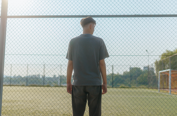 man standing in front of a fence