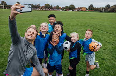 Male coach taking a selfie with his junior soccer team