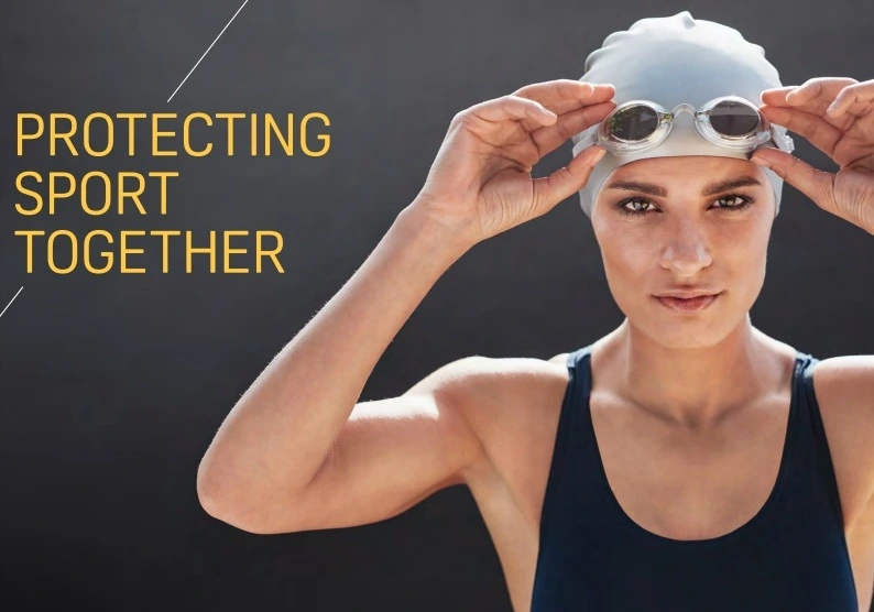 Swimmer in dark blue bathing suit and silver swimming cap putting goggles on