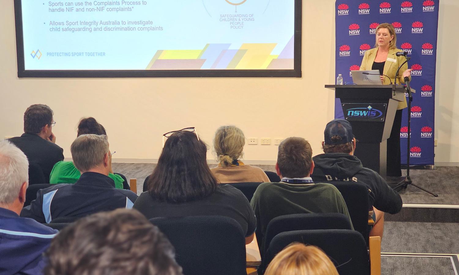 Sport Integrity Australia staff member at podium and presenting on screen