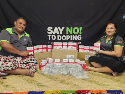 Samoa Medical and Anti-Doping Agency team members sit in front of a banner saying 'say no to doping' and display anti-doping test devices