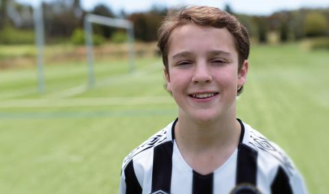 Junior footballer Harry in a black and white striped soccer jersey