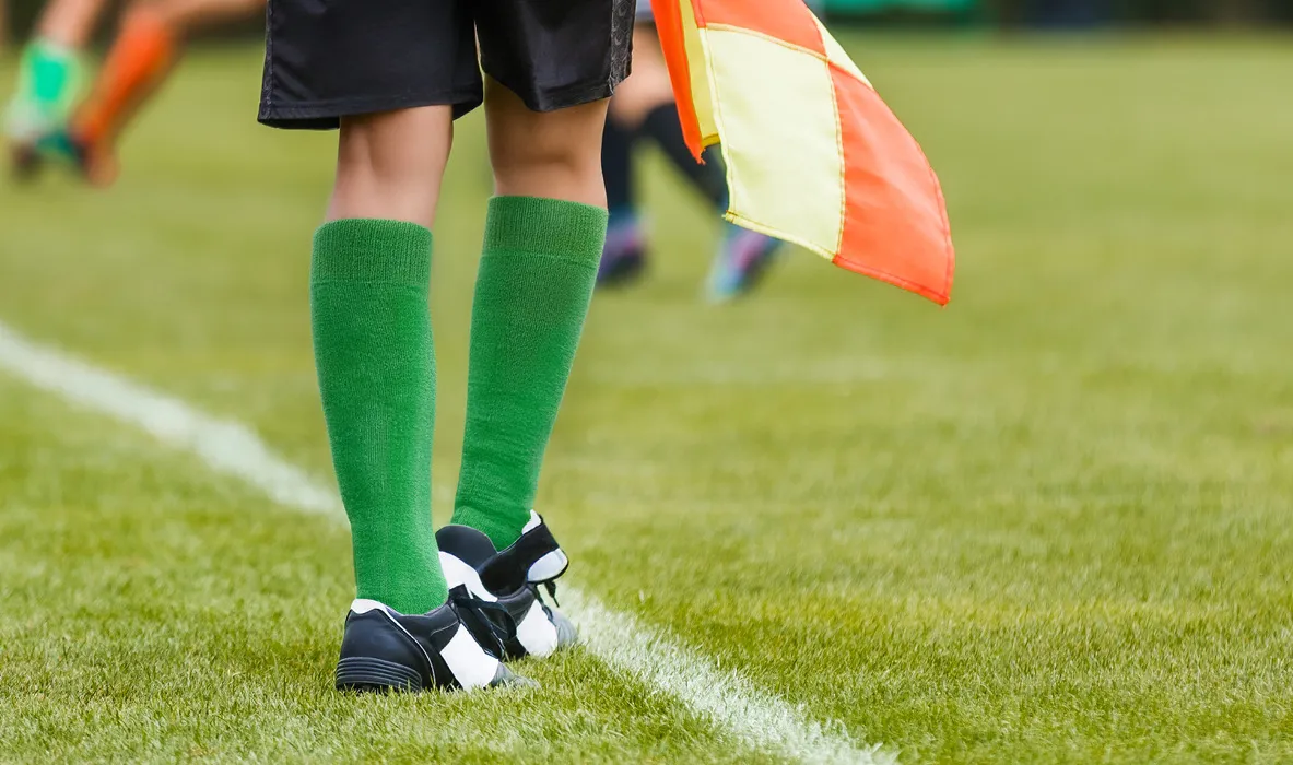 Lines official wearing green socks and holding a flag