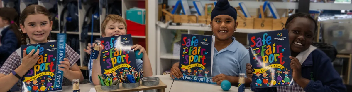 Primary school children holding up the Sport Integrity Australia children's activity book