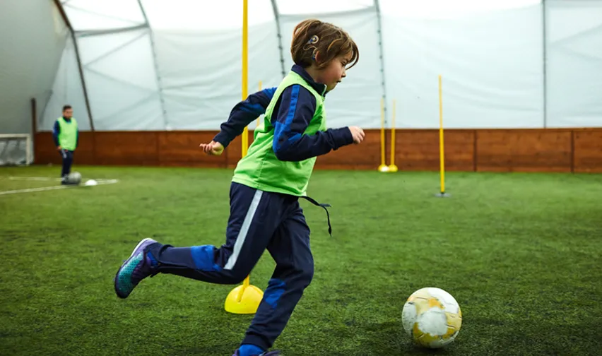 hearing impaired child kicking a soccer ball