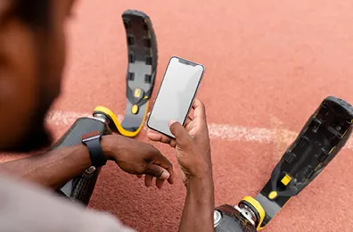 man with athletic leg prosthetics holding a mobile phone