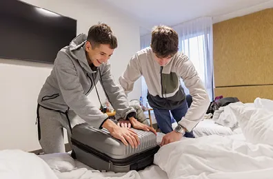 Two boys packing a suitcase in a hotel rooms
