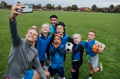 Male coach taking a selfie with his junior soccer team