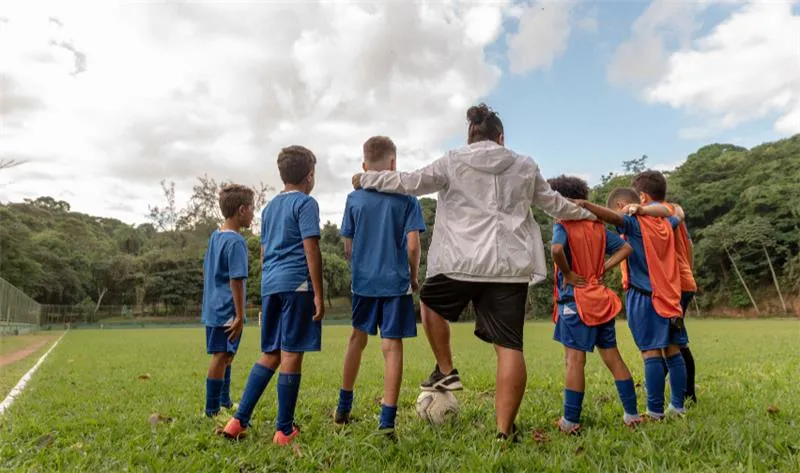 Coach and team huddle together on a soccer pitch