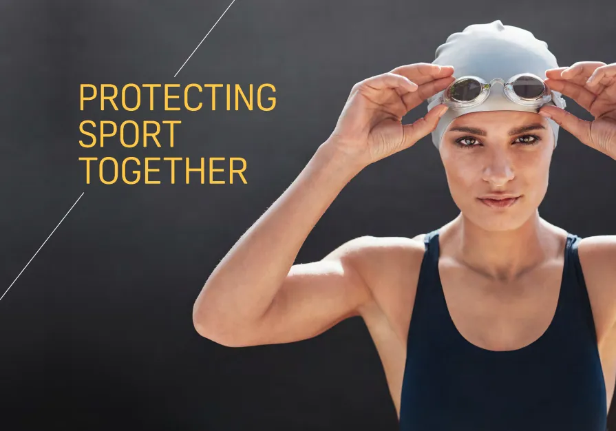 Female swimmer in swimming cap putting goggles on. 