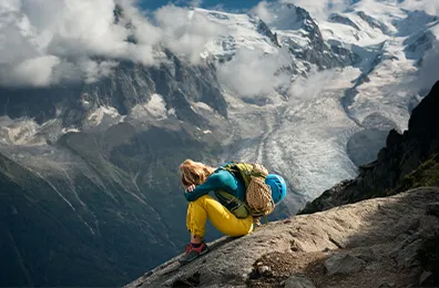 person sitting with head on their knees on a mountain