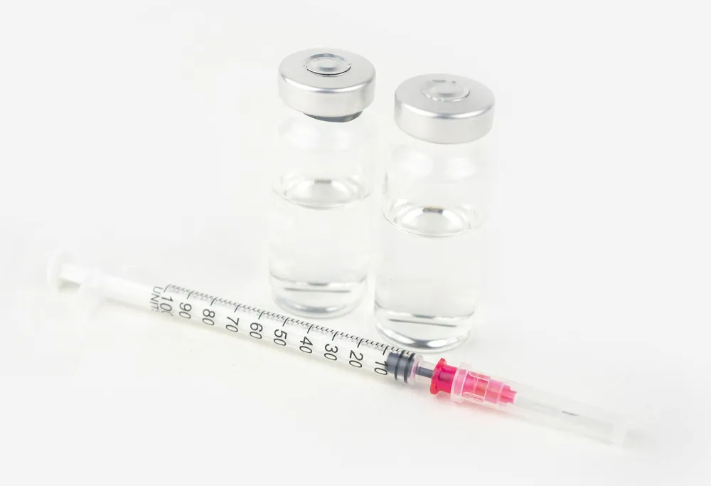 Two medical vials containing EPO behind a syringe