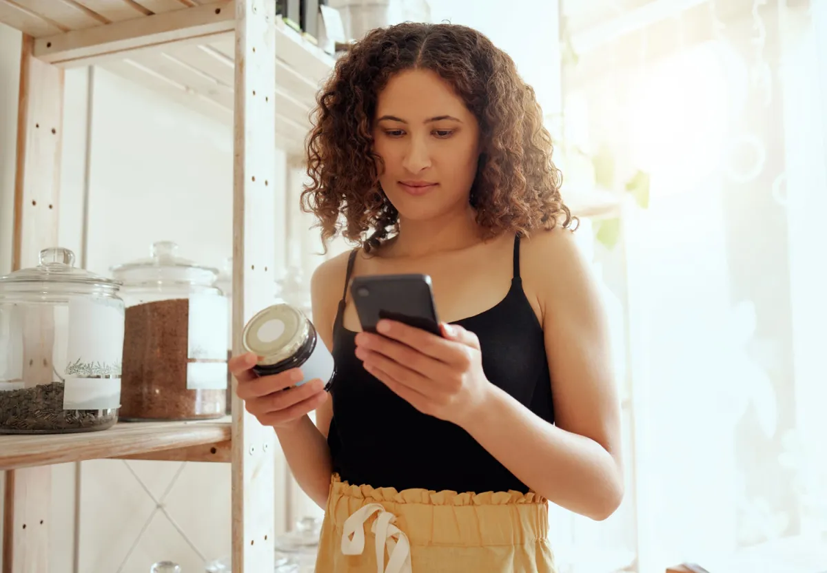 Teenage girl ponders supplement while checking mobile phone